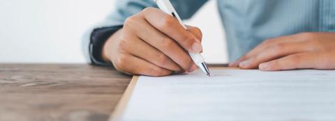 Close up of a hand writing with a pen on paper
