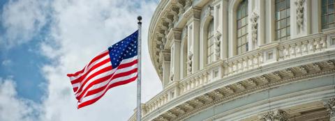 Close up of the United States capitol building and an American flag flying in the wind