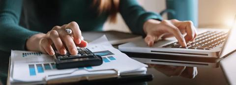 Woman working on a computer and calculator