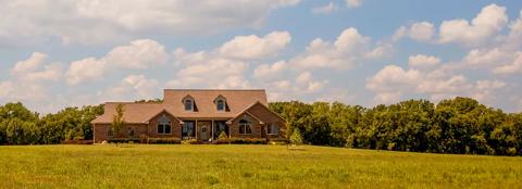 home in the country with green trees and field