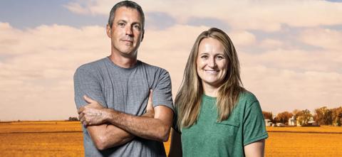 husband and wife posing in front of corn field in the fall