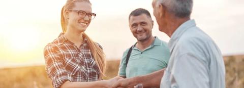 Woman shaking hands with man outside in field 