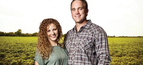 husband and wife posing in front of bean field in summer