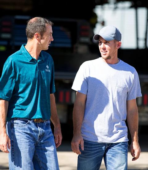 two men talking while walking on a farm 