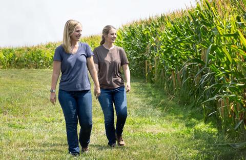 Two women producers walking next to cornfield checking the crop