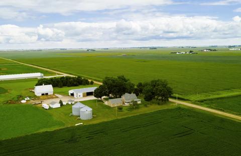 landscape with a patchwork of fields and a family home surrounded by farm buildings