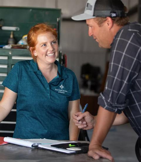 Farm Credit Services of America teammate speaking with customer next to farm equipment