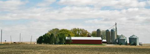 red farm building surrounded by a harvested field