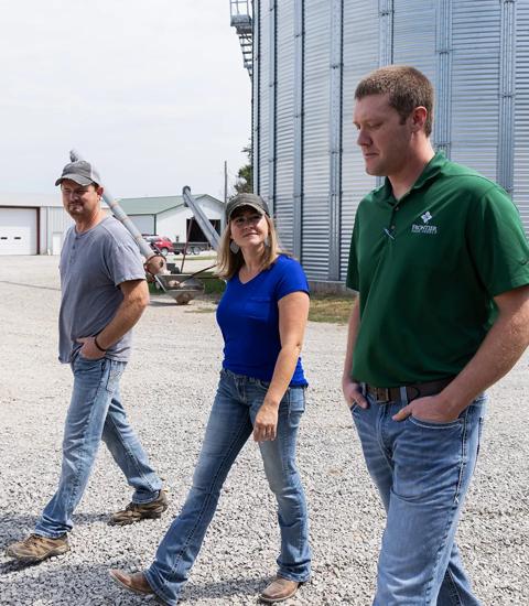 men and woman walking on a farm by sheds and grain bin 