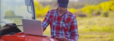 man in red flannel shirt working on computer outside.