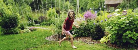 young child playing in a sprinkler