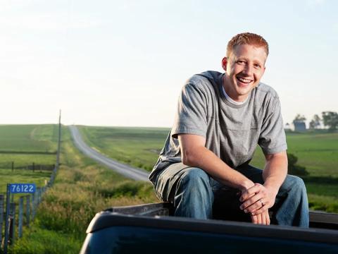 Man sitting on truck bed on the side of the country road