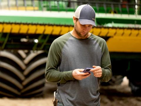 farmer looking at phone while in machine shed