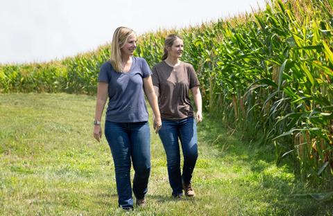 Two women producers walking next to cornfield checking the crop