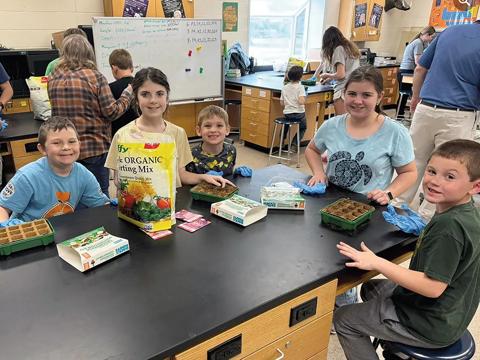 Students at a table planting seed in small containers