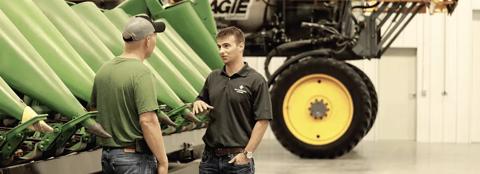 two men talking next to a combine