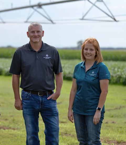 Two Farm Credit Services of America teammates standing near a field