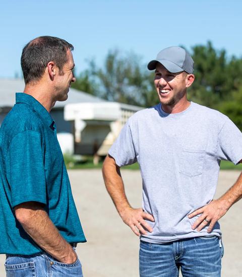 two men talking outside on a farm 