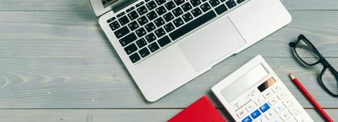 laptop, glasses, calculator and pencil on wooden desk